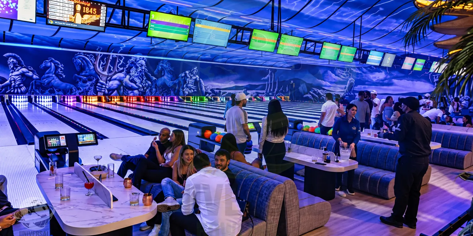 Home Zona lounge y pistas en un centro de bowling en operación, con clientes jugando y socializando